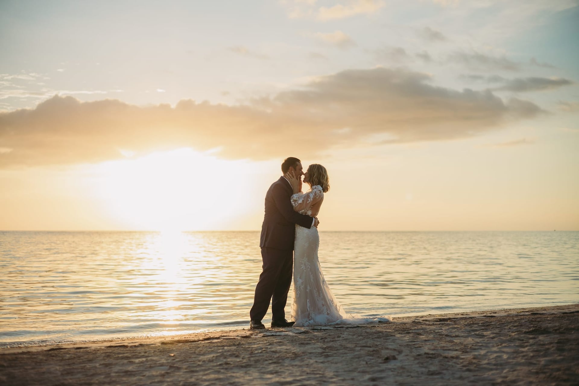 Husband and wife in their wedding attire on the beach duting sunset