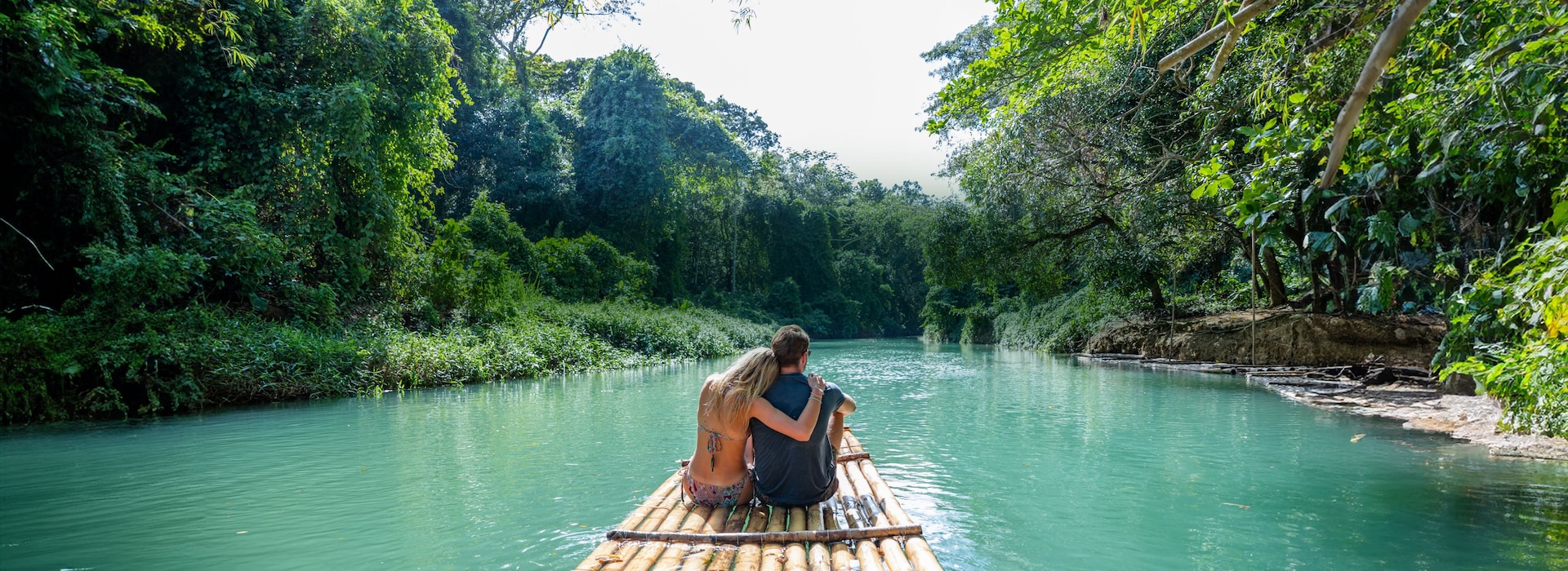 Couple floating down a beautiful river on a bamboo raft